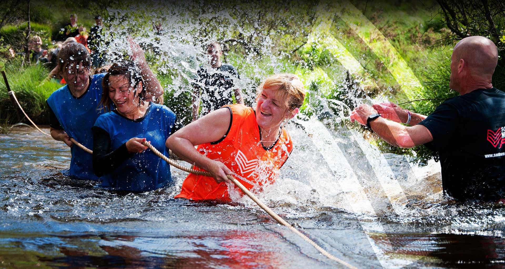 Members hauling on a rope in a river while the instructor shouts encouragement